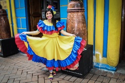 Eine Frau mit einem traditionellen gelb, blau, roten Kleid aus Kuba