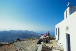 Familie guckt auf die Landschaft von Naxos und steht neben einer weißen Kirche 
