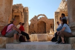 Eine Gruppe von Leuten sitzt auf den Treppen einer Ausgrabung in Amman