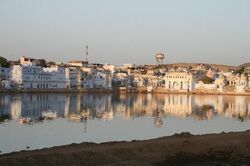 Ein See in Rajasthan, in dem sich die Stadt im Hintergrund spiegelt