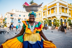 Eine traditionell bunt gekleidete Frau aus Kuba mit Obst auf dem Kopf 