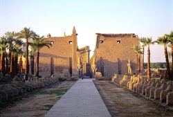 Ein Weg zu eienm historischen Tempel mit Palmen auf der Seite